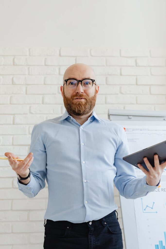 Bald man with beard presenting with a tablet in a modern office setting.